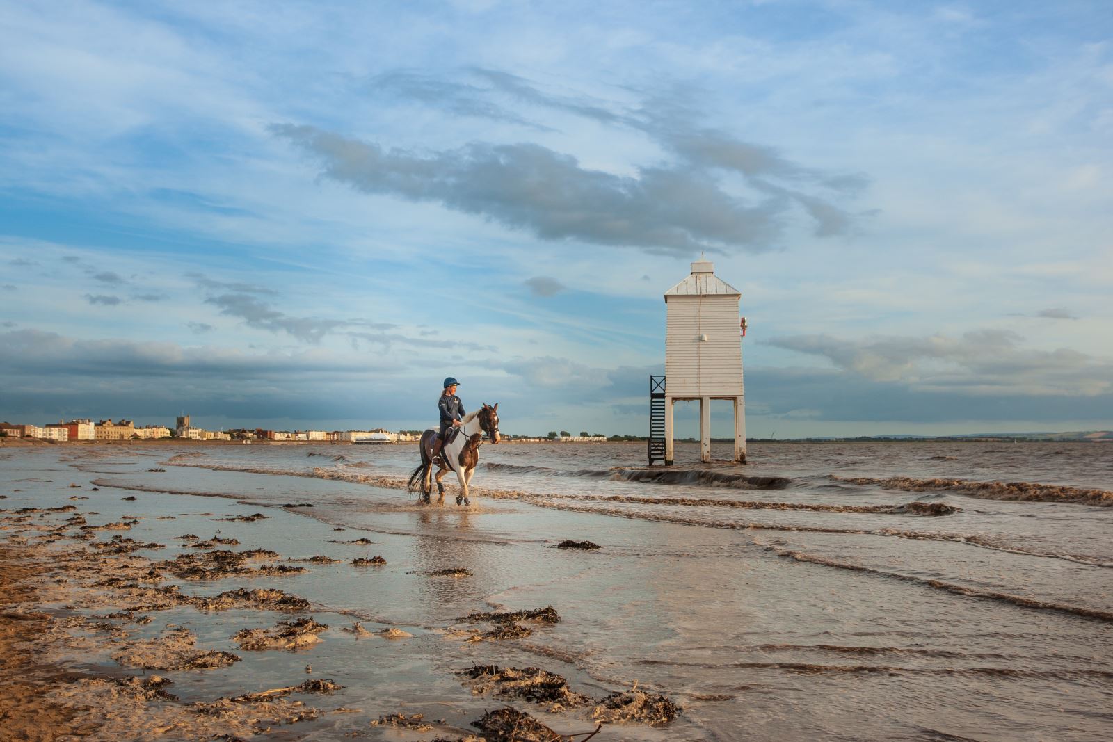 A horse and rider on the beach riding past the Low Lighthouse at Burnham-on-Sea