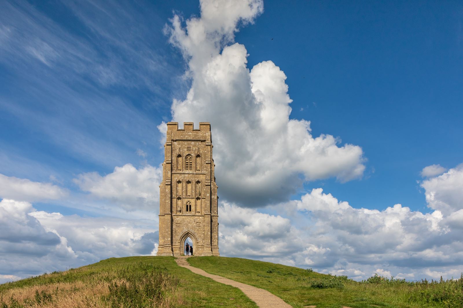 St Michael's Tower looking resplendent under blue skies with perfect white clouds as it sits on top of Glastonbury Tor