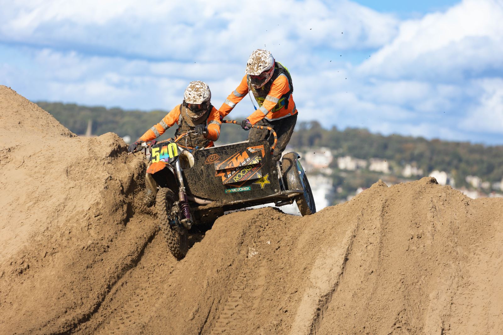 A motorbike and sidecar race over a sand dune at the Weston-super-Mare Beach Race