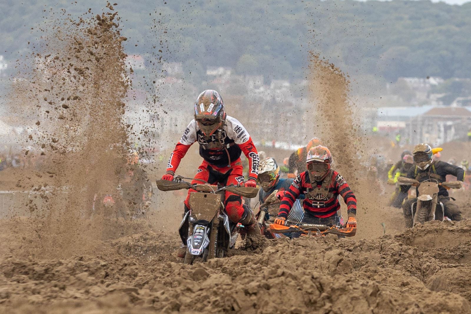 Sand flies up in an arc behind the riders at the Weston-super-Mare beach motorbike race