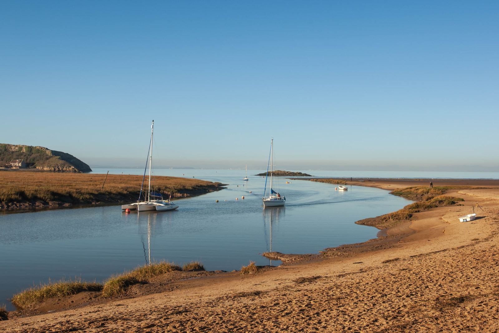 Uphill Beach on a sunny day with boats in the estuary