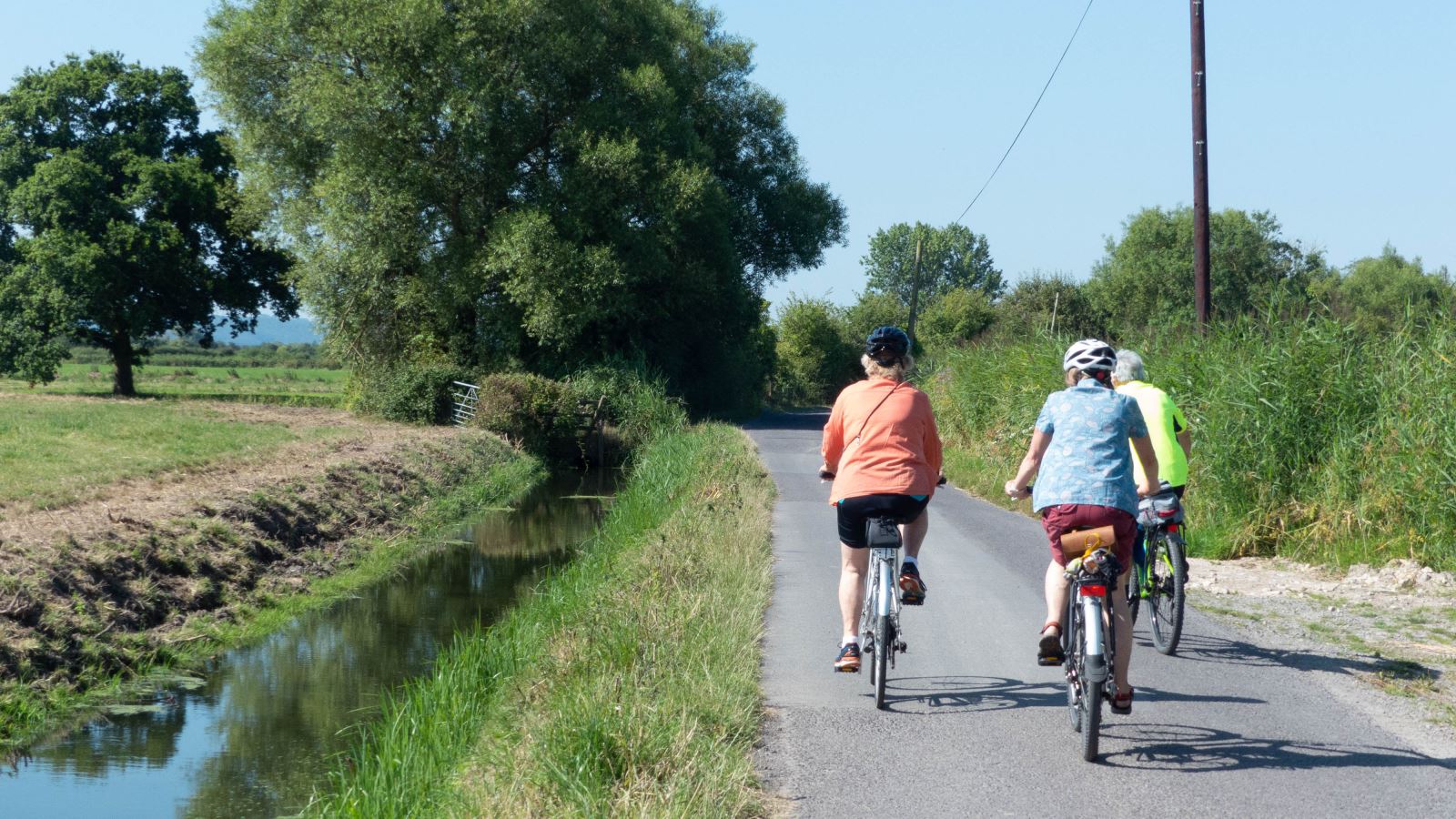 Back view of two cyclists on a lane flanked by a river